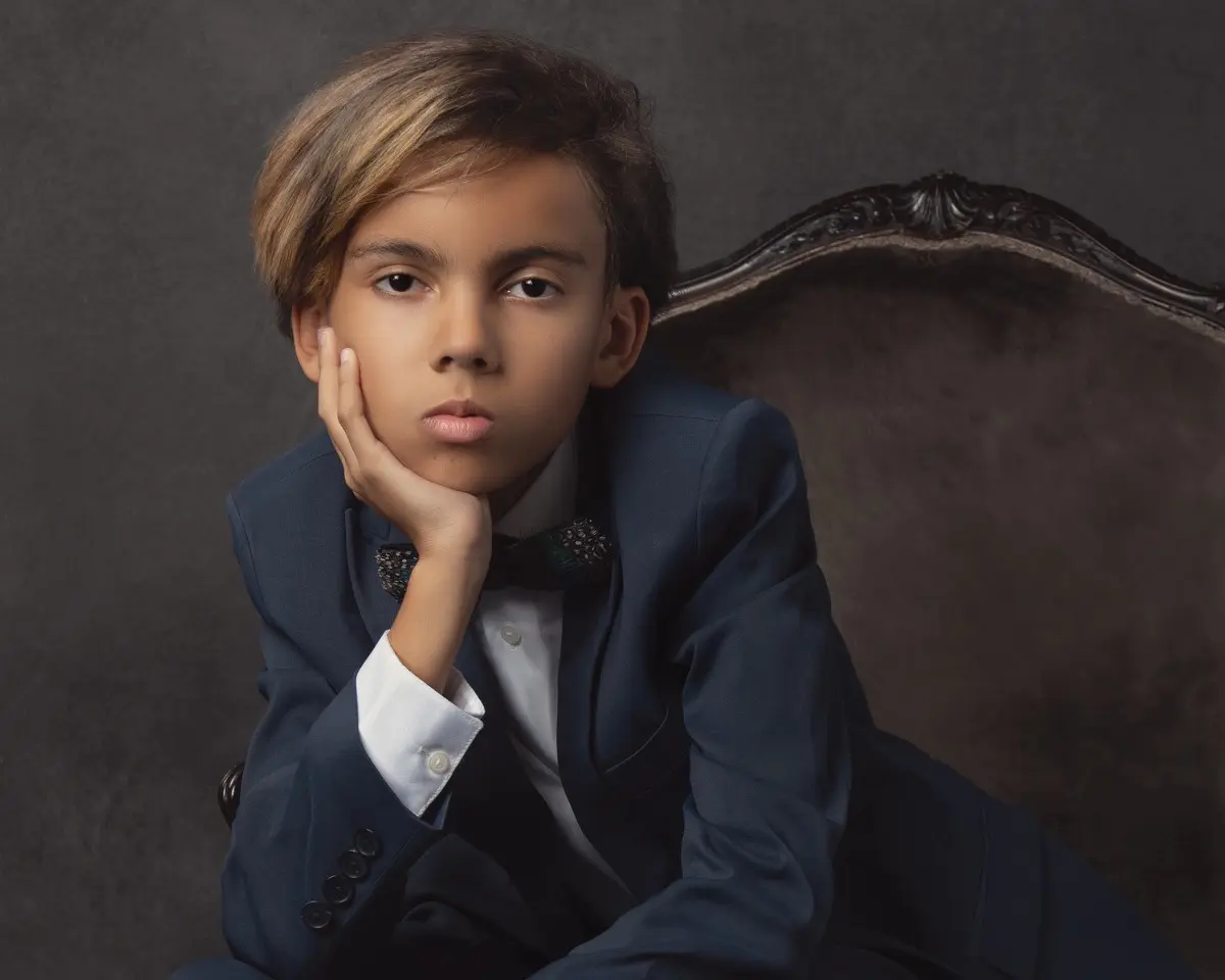Teen aged boy sitting with head in hand contemplating